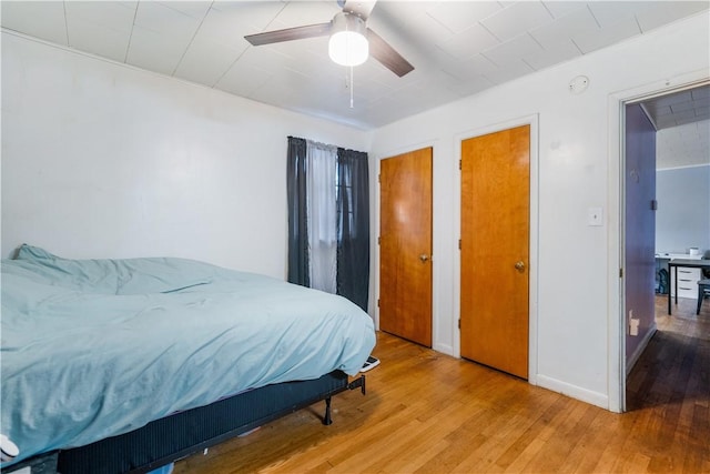 bedroom with hardwood / wood-style floors, ceiling fan, and multiple closets