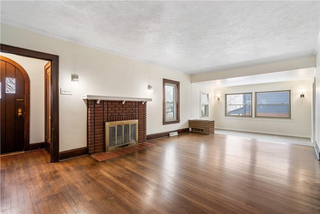 unfurnished living room with a fireplace, a textured ceiling, and dark hardwood / wood-style flooring