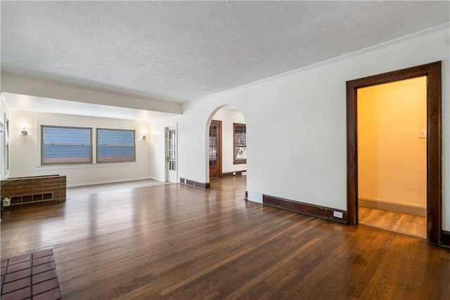 empty room with dark hardwood / wood-style flooring, a textured ceiling, and ornamental molding