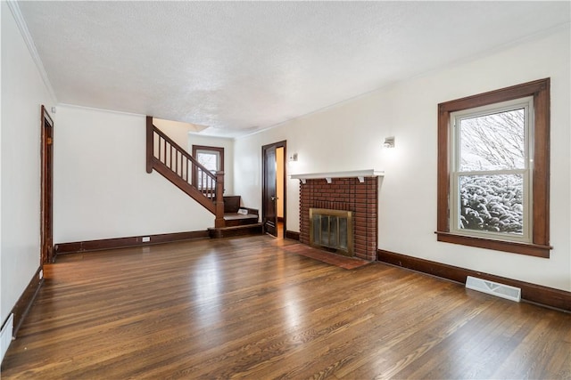 unfurnished living room featuring a fireplace, dark hardwood / wood-style flooring, a textured ceiling, and crown molding