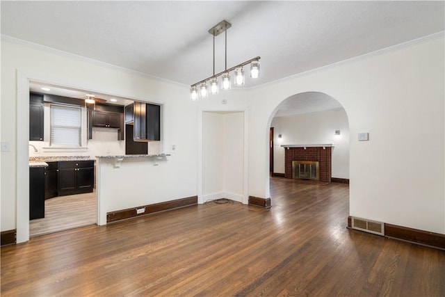 interior space with crown molding, dark hardwood / wood-style floors, and a brick fireplace