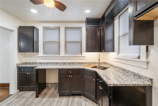 kitchen featuring light stone countertops, ceiling fan, sink, light hardwood / wood-style floors, and dark brown cabinets