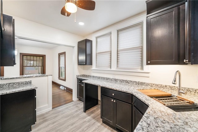 kitchen featuring dark brown cabinetry, ceiling fan, light stone countertops, and light wood-type flooring