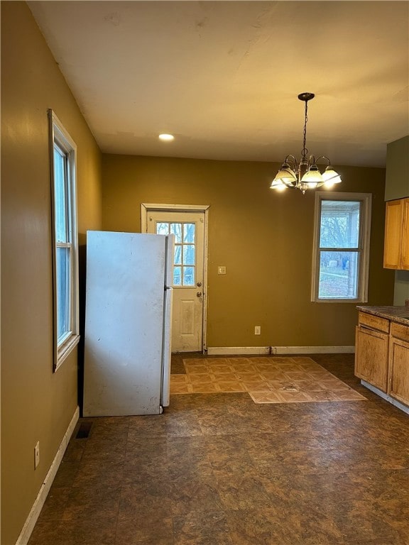 kitchen featuring plenty of natural light, white refrigerator, decorative light fixtures, and a chandelier