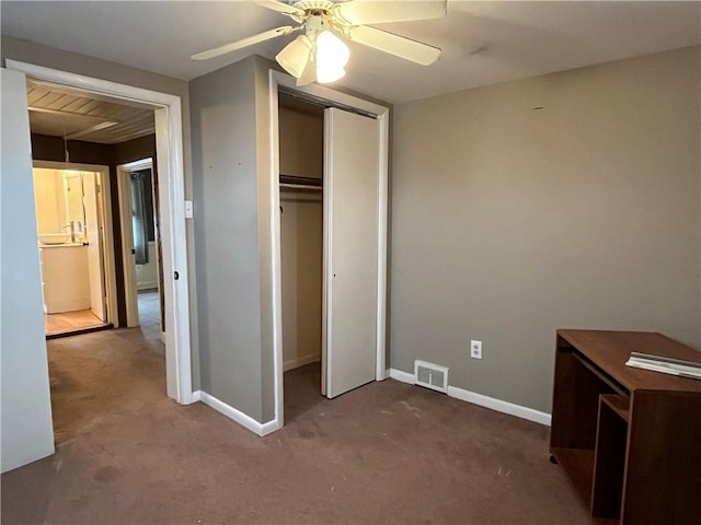 unfurnished bedroom with dark colored carpet, a closet, and ceiling fan