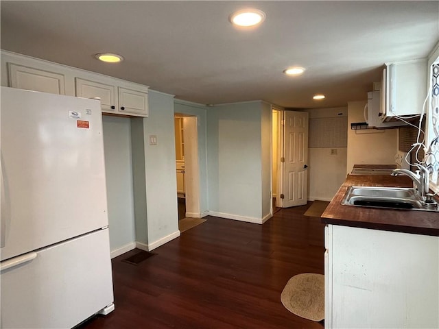 kitchen featuring dark wood-type flooring, sink, butcher block countertops, white fridge, and white cabinetry