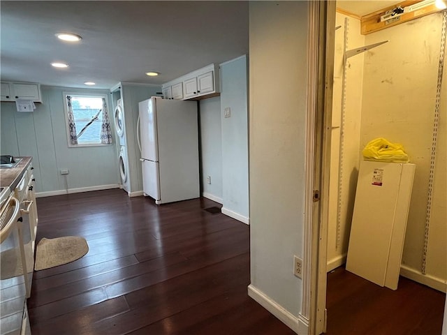 kitchen with white cabinetry, dark hardwood / wood-style flooring, white fridge, and stacked washer and clothes dryer