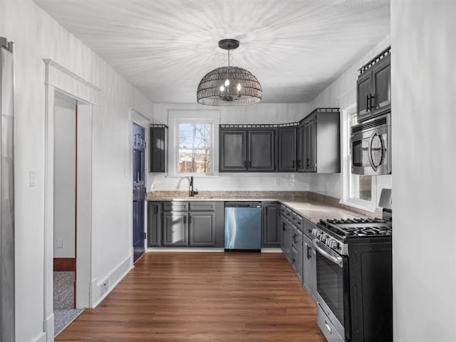 kitchen with gray cabinetry, stainless steel appliances, dark wood-type flooring, sink, and a notable chandelier