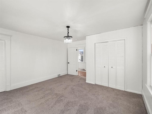 unfurnished bedroom featuring carpet flooring, a notable chandelier, and a closet