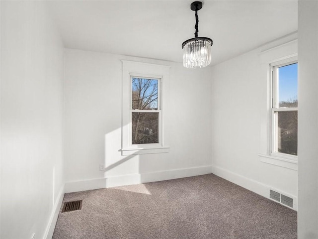 empty room with carpet floors and an inviting chandelier