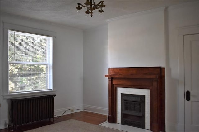 unfurnished living room featuring light wood-type flooring, radiator, ornamental molding, a textured ceiling, and an inviting chandelier