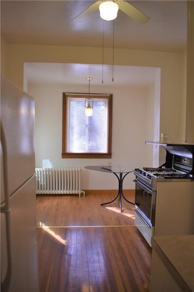 kitchen featuring refrigerator, gas range, hardwood / wood-style floors, pendant lighting, and radiator heating unit