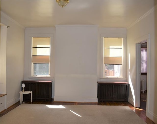 unfurnished room featuring crown molding, radiator heating unit, and dark hardwood / wood-style floors