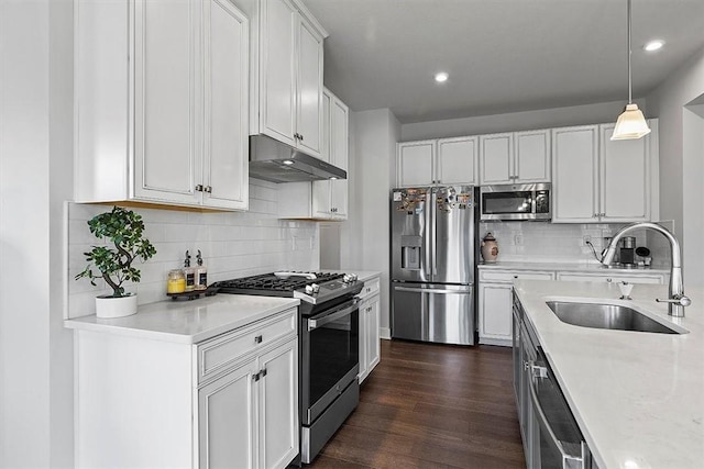 kitchen featuring white cabinetry, sink, dark hardwood / wood-style flooring, pendant lighting, and appliances with stainless steel finishes