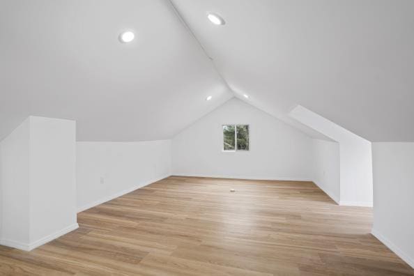 additional living space featuring lofted ceiling and light wood-type flooring