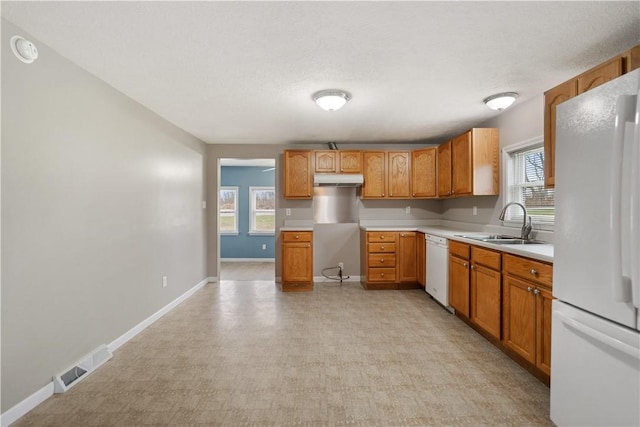 kitchen with a textured ceiling, a healthy amount of sunlight, white appliances, and sink