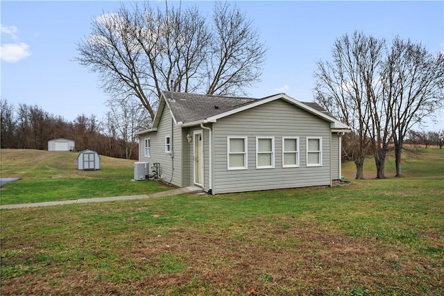 view of side of property with cooling unit, a storage shed, and a lawn