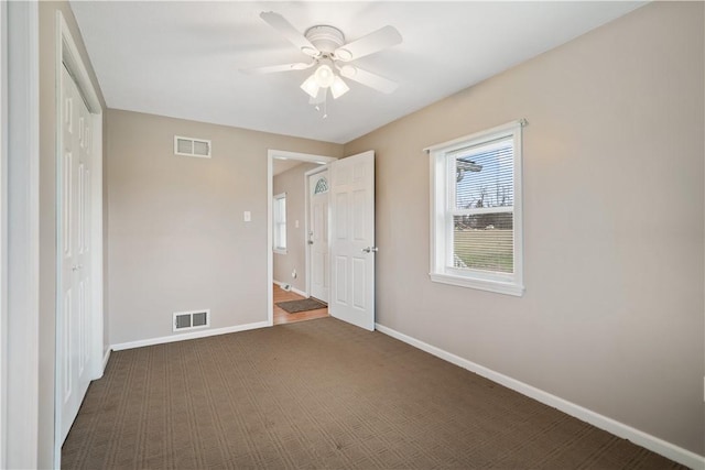 unfurnished bedroom featuring dark colored carpet, a closet, and ceiling fan