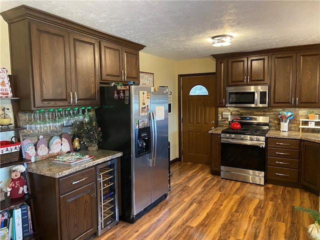 kitchen with decorative backsplash, dark brown cabinets, stainless steel appliances, dark hardwood / wood-style floors, and wine cooler