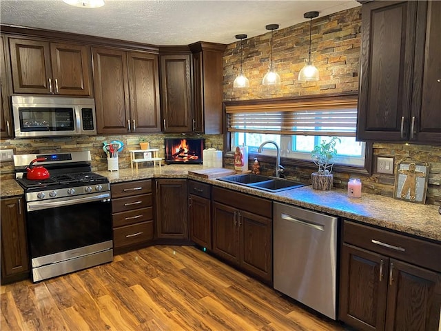 kitchen with pendant lighting, sink, wood-type flooring, and stainless steel appliances