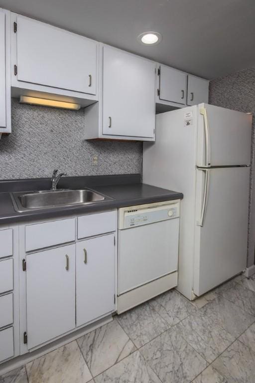 kitchen with dark countertops, white appliances, white cabinetry, and a sink