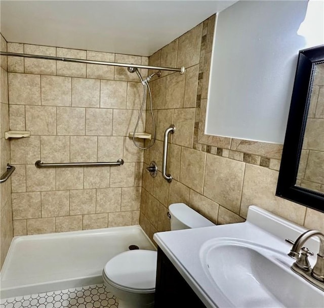 bathroom featuring toilet, a stall shower, vanity, and tile walls