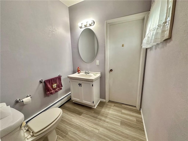 bathroom featuring hardwood / wood-style flooring, vanity, toilet, and baseboard heating