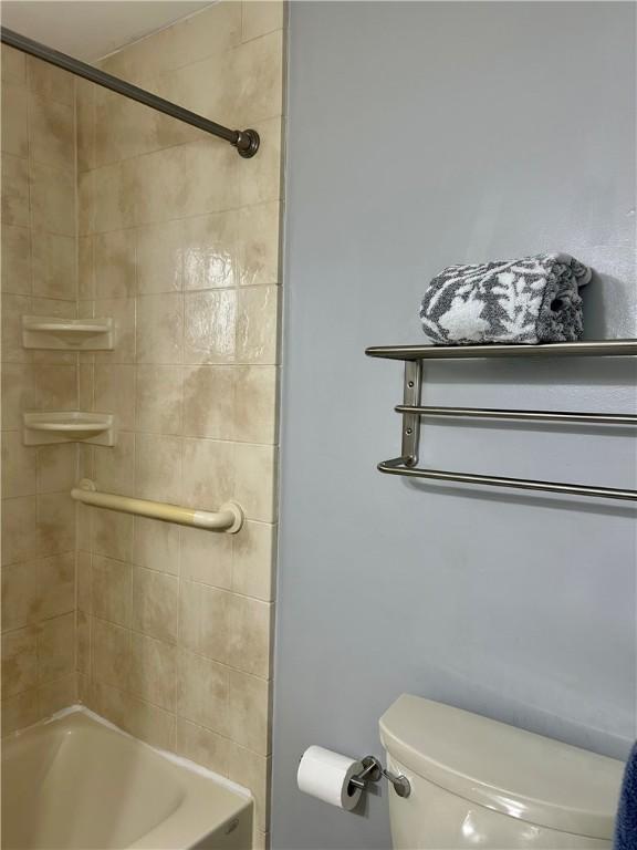 bathroom featuring tiled shower / bath combo and toilet