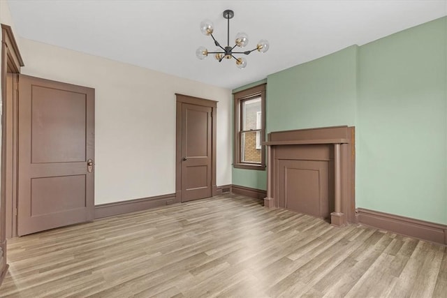 unfurnished living room featuring a chandelier and light hardwood / wood-style floors