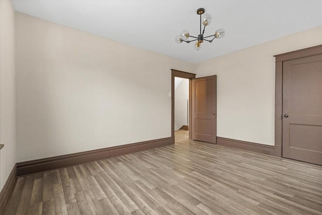 unfurnished room featuring light hardwood / wood-style floors and a chandelier