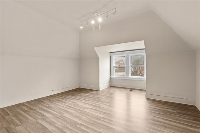 additional living space featuring lofted ceiling and light hardwood / wood-style flooring