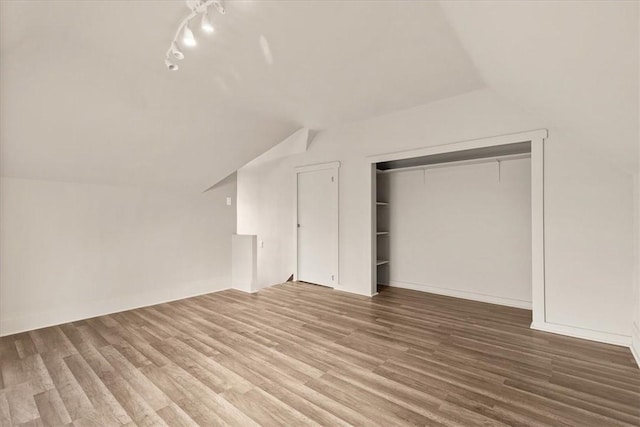 unfurnished bedroom featuring hardwood / wood-style floors, vaulted ceiling, and a closet