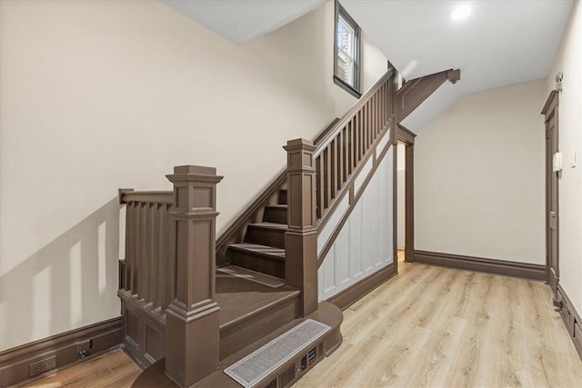 stairway with wood-type flooring and lofted ceiling