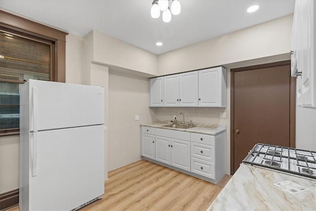 kitchen featuring white cabinets, white refrigerator, light hardwood / wood-style floors, and sink