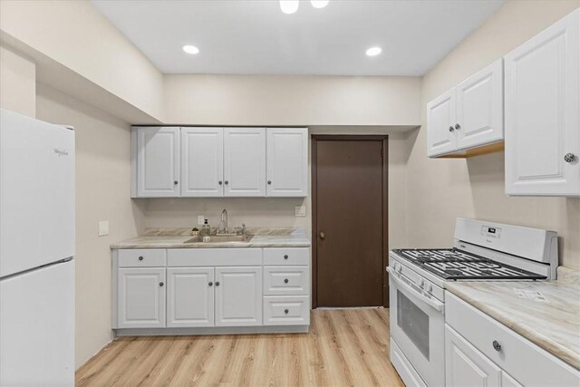 kitchen featuring white cabinetry, white appliances, sink, and light hardwood / wood-style flooring