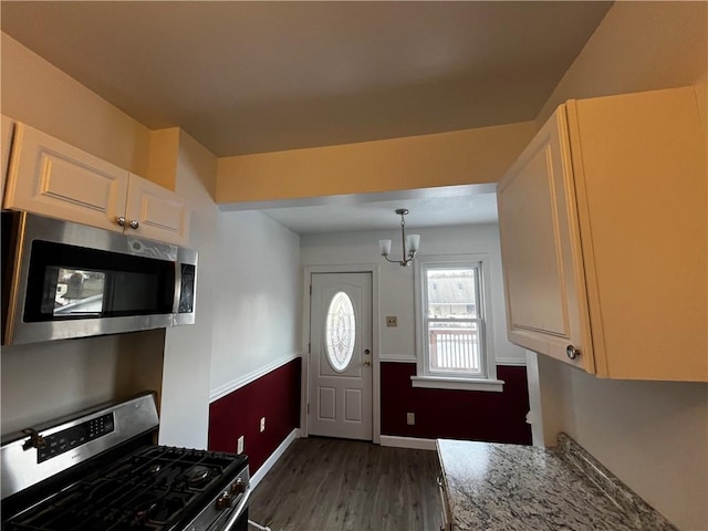 kitchen featuring white cabinetry, dark wood-type flooring, a notable chandelier, decorative light fixtures, and appliances with stainless steel finishes