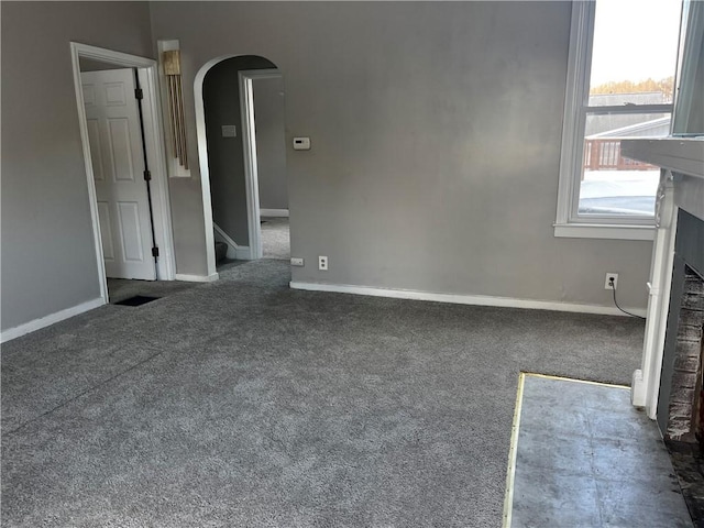 unfurnished living room with a fireplace and dark carpet