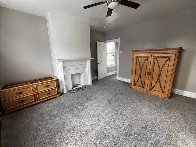 unfurnished living room with ceiling fan, a fireplace, and dark carpet