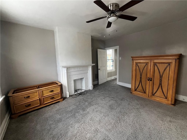 unfurnished living room with ceiling fan, dark carpet, and a brick fireplace