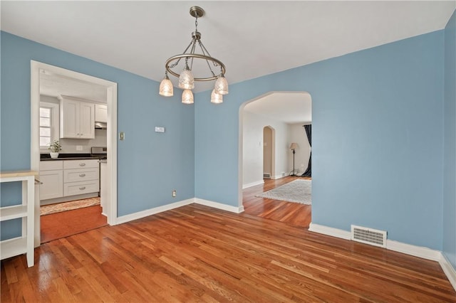 unfurnished dining area featuring wood-type flooring and a notable chandelier