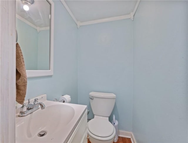 bathroom with wood-type flooring, vanity, toilet, and crown molding