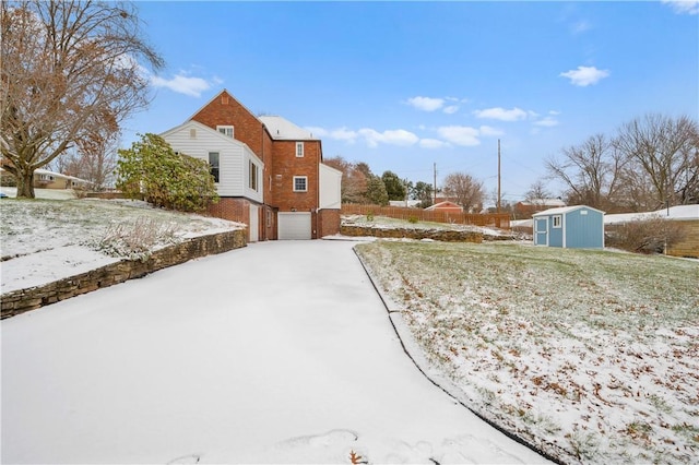 yard covered in snow featuring a shed and a garage