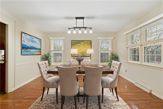 dining space featuring baseboard heating, a wealth of natural light, and hardwood / wood-style floors