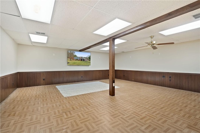 basement with a paneled ceiling, light parquet floors, and ceiling fan