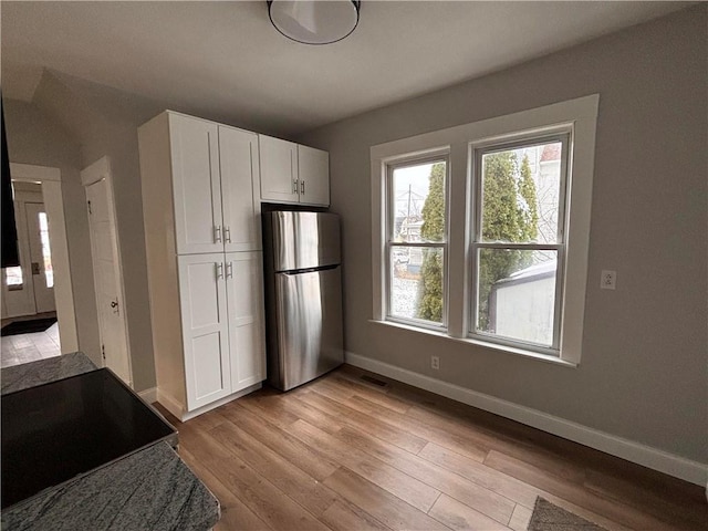 kitchen featuring white cabinets, stainless steel fridge, light hardwood / wood-style floors, and range