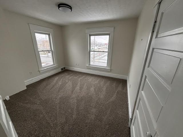 spare room with dark colored carpet