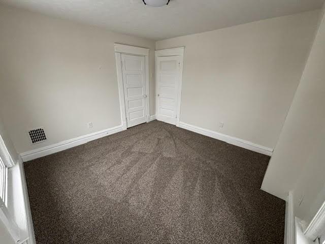 unfurnished bedroom featuring dark carpet