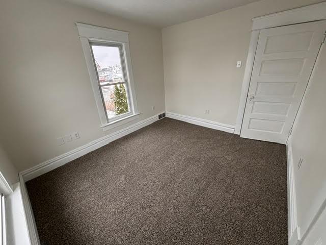 spare room featuring dark colored carpet