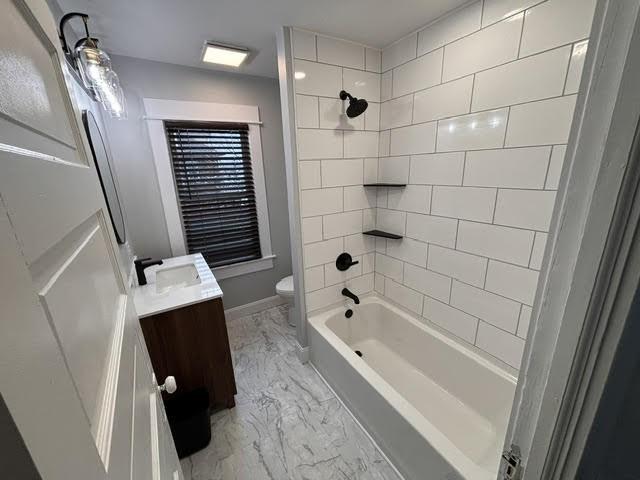 full bathroom featuring toilet, vanity, and tiled shower / bath