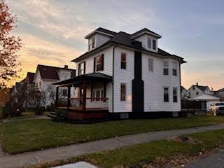 property exterior at dusk featuring a yard and a porch